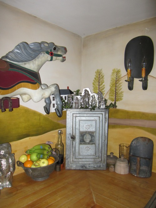 A child size C.W. Parker carousel horse that we restored gallops across the Rufus Porter style mural that I painted in the kitchen.